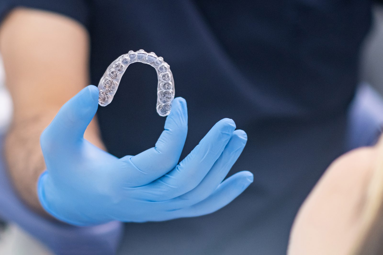 Aligneur dentaire transparent tenu dans une main gantée
